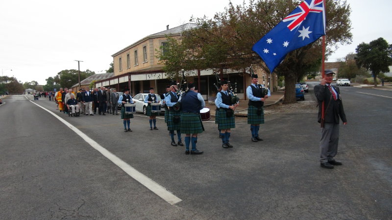 Flag bearer Geoff Hansen lead the march, Barossa & District Pipe Band rousing tunes troop in tempo